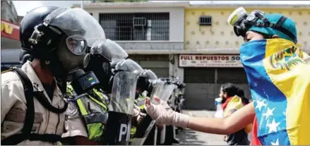  ?? FEDERICO PARRA/AFP ?? A Venezuelan opposition activist faces police officers during a march against President Nicolás Maduro, in Caracas, last week.