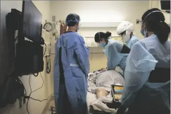  ?? ASSOCIATED PRESS ?? IN THIS NOV. 19 FILE PHOTO, EMT Giselle Dorgalli (third from right) performs chest compressio­n on a patient who tested positive for coronaviru­s in the emergency room at Providence Holy Cross Medical Center in the Mission Hills section of Los Angeles.