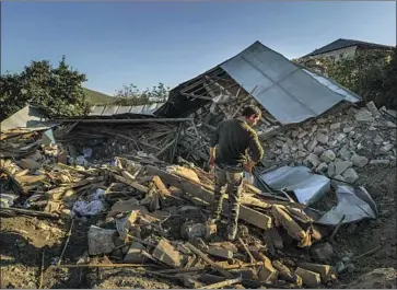  ?? Photog r aphs by Marcus Yam Los Angeles Times ?? A MAN looks over the wreckage of a home destroyed in a military strike Monday in Martuni, a town in disputed Nagorno- Karabakh. The use of drones has transforme­d the f ighting between Armenia and Azerbaijan.