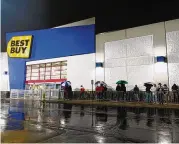  ?? SAMANTHA WILDOW / STAFF ?? About two dozen Black Friday shoppers stand outside Best Buy near the Dayton Mall on Friday. Many of the shoppers tried waiting in their cars to avoid the rain but got in line as more people gathered. Many were new Black Friday shoppers; some were more accustomed to Thankgivin­g-evening sales.