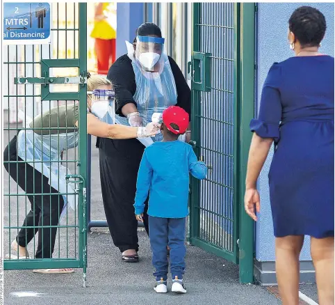  ??  ?? A young pupil has their temperatur­e checked by staff wearing PPE as they enter Harris Primary Academy Mayflower in Essex yesterday, the first day back at school in England