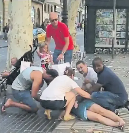  ?? AFP ?? Víctima. Un grupo de personas ayuda a una mujer arrollada por una de las furgonetas en Barcelona.