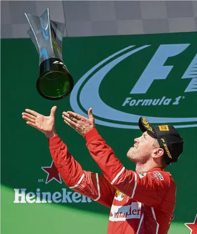  ??  ?? High five: Ferrari’s Sebastian Vettel celebratin­g on the podium with his trophy after winning the Brazilian Formula One Grand Prix at the Interlagos circuit in Sao Paulo on Sunday. It was the German’s fifth win of the season. — AFP