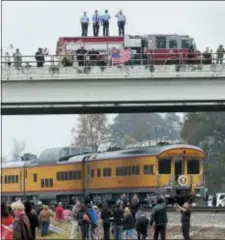  ?? MICHAEL WYKE — THE ASSOCIATED PRESS ?? Firefighte­rs stand on their truck and salute along with other attendants on an overpass as the train carrying the body of former president George H.W. Bush travels past on the way to Bush’s final internment Thursday in Spring, Texas.