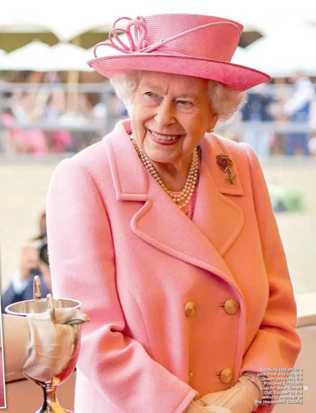  ??  ?? Looking radiant in a pink coat and hat, the Queen presents the Princess Elizabeth Cup for Best Turned Out Trooper to the winning member of the Household Cavalry