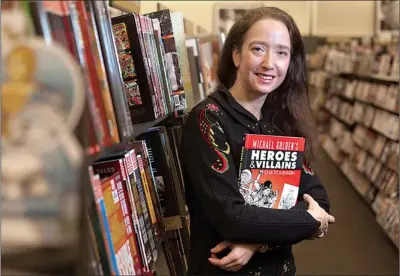  ?? Staff photo by Doug Strickland ?? Renee Witterstae­tter, a writer, comic book editor and color artist who has worked for Marvel and DC Comics, holds a copy of one of her books, Michael Golden’s “Heroes & Villains Sketchbook,” on Friday in the graphic novels section of Books-A-Million in...