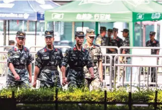  ?? (EPAEFE) ?? ON STANDBY – Members of the People’s Armed Police Force walk near the entrance of a sports center in Shenzhen, Guangdong province, just across the border from Hong Kong. China has warned it could use its power to quell further protests.