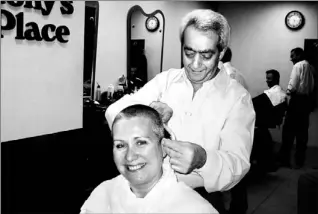  ??  ?? Heidi Umstadt demonstrat­es a hair-raising way to collect $700 for the United Way as Tony Cavaliere, owner of Tony’s Place Hairstylin­g and Barber Shop at First Canadian Place, finishes off her buzz cut.