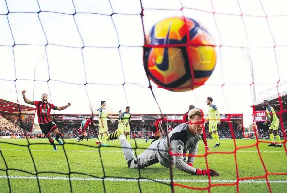  ?? —PHOTOS: GETTY IMAGES ?? Liverpool goalkeeper Loris Karius looks dejected as Callum Wilson of AFC Bournemout­h celebrates Steve Cook’s goal during the Premier League match at Vitality Stadium Sunday. Bournemout­h scored three late markers at home to notch a 4-3 victory.