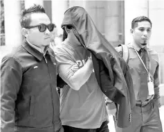  ??  ?? Malaysian Anti-Corruption Commission (MACC) officers escorting the suspect, a senior police officer with the title of ‘Datuk' to the Magistrate's Court to obtain his remand order. - Bernama photo