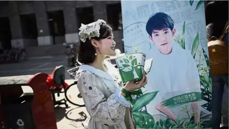  ??  ?? No fleeting fancy: A woman handing out leaflets during an event for fans of China’s boy band sensation TFBoys at a university in Beijing. — AFP