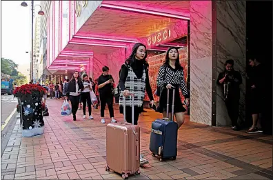  ?? AP ?? Chinese tourists walkon the Canton Road, the one-stop-shopping street of high-end brands in Hong Kong, in late November. Chinese purchases of luxury goods from designer boutiques of Manhattan and Paris are down this year amid cooling economic growth in China.