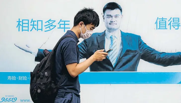  ?? ?? Un jove consulta el mòbil mentre passa per davant de la seu a Xangai d’una de les companyies puixants del gegant asiàtic, China Life