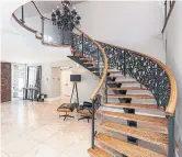  ??  ?? The curved, oak-and-wrought-iron staircase makes a dramatic statement in the main foyer.