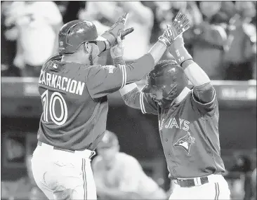  ?? NATHAN DENETTE/THE CANADIAN PRESS VIA ASSOCIATED PRESS ?? Toronto’s Edwin Encarnacio­n (10) and Jose Bautista celebrate at home plate after scoring on a double by Troy Tulowitzki against Kansas City during Game 5 of the American League Championsh­ip Series. The Blue Jays won 7-1 to force a Game 6.