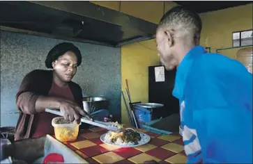  ?? Photograph­s by Hayne Palmour IV San Diego Union-Tribune ?? THERESA MOISE, a cook at Labadee restaurant in Tijuana, serves fellow Haitian Kesmer Mollisoint a plate of Haitian food. Many immigrants from their country have found work in the border city’s service sector.