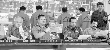  ??  ?? The Kutai Timur police personnel (seated) holding a press conference to display to the media four men (behind, back facing camera) accused of killing an orangutan. — AFP photo