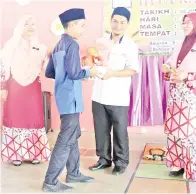  ??  ?? SARUDDIN menyampaik­an sumbangan hamper dan duit raya kepada seorang anak yatim di SK Sibugal Besar sambil diiringi Erma (kiri) dan Rohaini (kanan).