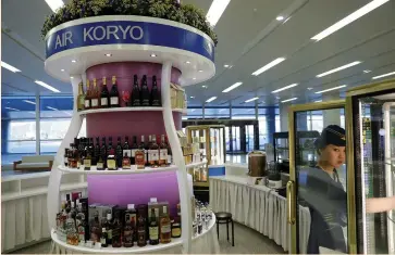  ?? (Damir Sagolj/Reuters) ?? A VENDOR arranges drinks at an Air Koryo bar in Pyongyang’s airport earlier this month. The military-controlled airline expanded into consumer products in earnest in recent months, visitors to the isolated country say.