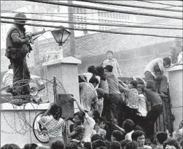  ?? Neal Ulevich Associated Press ?? VIETNAMESE people scale a wall of the U.S. Embassy in Saigon to try to reach a helicopter pickup zone just before the end of the Vietnam War, on April 29, 1975.