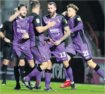  ??  ?? GOAL-DEN MOMENT: Tom Pope is congratula­ted by team-mates after netting the equaliser at Morecambe, before Pope runs off to acknowledg­e the cheers of the travelling fans.