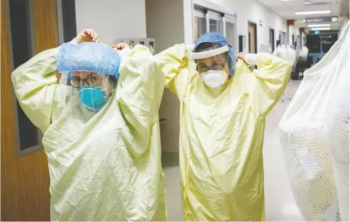  ?? COLE BURSTON / AFP VIA GETTY IMAGES FILES ?? Health-care workers don personal protective equipment as they prepare to enter the room of a patient suffering
from COVID-19 at Humber River Hospital’s Intensive Care Unit in Toronto.