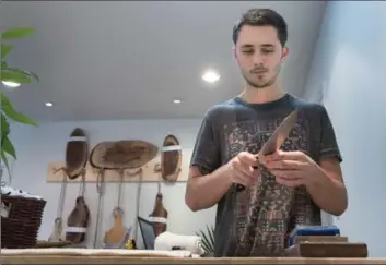  ??  ?? Gage Corlett, owner of Sharp Knife Shop on James Street South, uses a whetstone to sharpen a customer’s knife.