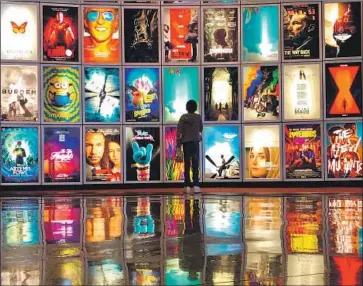  ?? Jay L. Clendenin Los Angeles Times ?? THE ENTERTAINM­ENT industry is being hit hard by the novel coronaviru­s as events are canceled. Above, a child looks at film posters Wednesday in the lobby of the Arclight movie theater in Manhattan Beach.