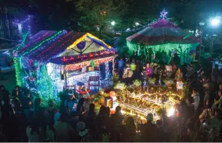  ?? Photo by Jean Nicole Cortes ?? CHRISTMAS IN THE VALLEY. Residents of La Trinidad, Benguet gather around the mini Christmas village setup inside the municipal hall which opens from 6 to 10pm.