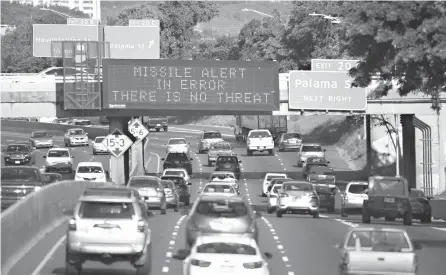  ?? Anthony Quintano/Civil Beat via Associated Press ?? Cars drive Saturday past a highway sign that says “MISSILE ALERT IN ERROR THERE IS NO THREAT” on the H-1 Freeway in Honolulu. State emergency officials announced human error as a cause for a statewide announceme­nt of an incoming missile strike alert...