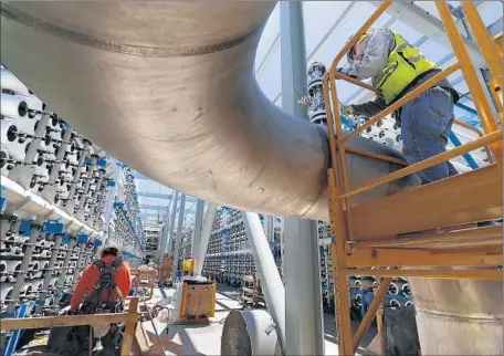  ?? Photog raphs by Don Bartletti
Los Angeles Times ?? PIPE FITTER Steven Montes, right, installs a pressure relief valve at the Carlsbad desalinati­on plant. For the desalinati­on industry, the plant presents a chance to disprove criticism that the technology is exorbitant­ly expensive, hogs energy and...