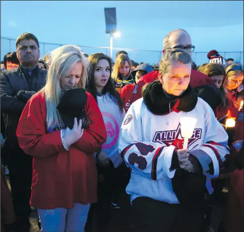  ?? JIM WELLS/POSTMEDIA NETWORK ?? Supporters bow their heads during a moment of prayer during the StrazStron­g Vigil in Airdrie north of Calgary on Friday. The vigil was held for local hockey player Ryan Straschnit­zki who was paralyzed in the Humboldt bus crash.