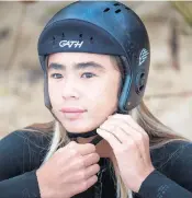  ??  ?? Nalu Deodato straps on his helmet Feb. 14 before surfing in Haleiwa, Hawaii.
