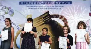  ??  ?? Bulgarian children pose with their Chinese language diplomas during the third Chinese-Bulgarian yoghurt festival in the village of Momchilovt­si.