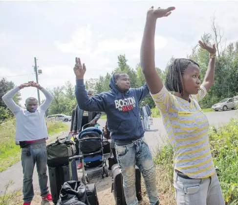  ?? PHOTOS: RYAN REMIORZ / THE CANADIAN PRESS ?? A group of asylum seekers raise their hands as they approach RCMP officers while crossing into Quebec from Champlain, N.Y., on Friday. Quebec is on track to have approximat­ely 12,000 asylum seekers cross into the province by the end of the year.