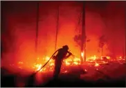  ?? Ap-noah Berger ?? A firefighte­r battles the Creek Fire as it threatens homes in the Cascadel Woods neighborho­od of Madera County, Calif., on Monday.