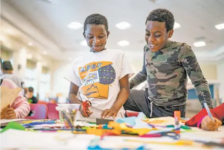  ?? ?? ABOVE: Students Sobeckukwu Abanifi, left, and Shachah Uzoho of Nigeria joke together while working on mixed media art pieces July 14 at the Newcomer Language Academy at Milagro Middle School.