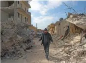  ?? AP PHOTO/GHAITH ALSAYED ?? A man walks past collapsed buildings Tuesday following a devastatin­g earthquake in the town of Jinderis, Aleppo province, Syria.