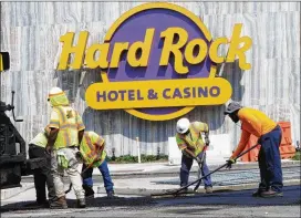  ?? AP ?? Workers rake asphalt outside the Hard Rock casino in Atlantic City, N.J. With the former Revel due to reopen as the Ocean Resort Casino, crews are scrambling to get it ready for Thursday.