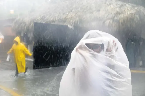  ??  ?? > A woman takes cover as Hurricane Maria approaches the Dominican Republic on September 20. This weekend’s bad weather is the tail end of Maria