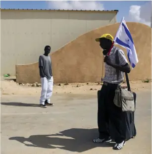  ?? (Amir Cohen/Reuters) ?? AN AFRICAN migrant holds an Israeli flag after being released from Holot detention center in 2015.