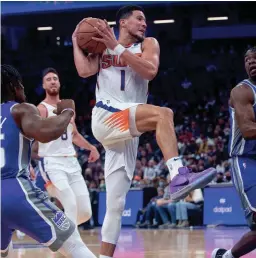  ?? ?? Suns guard Devin Booker (1) drives to the basket past Kings guards Davion Mitchell (15) and Terence Davis (3) on Monday.