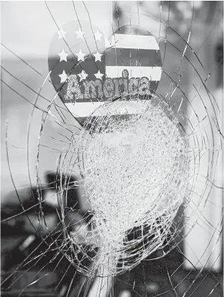  ?? ALYSSA SCHUKAR/THE NEW YORK TIMES ?? A sticker reading “America” is seen Aug. 25 in the window of a damaged business in Kenosha, Wisconsin.