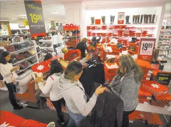  ?? Richard Brian ?? Las Vegas Review-journal @vegasphoto­graph Shoppers navigate the women’s boot section Thursday at J.C. Penney at the Meadows Mall. At one point, a line to the store snaked around the building and down the sidewalk.