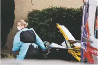  ?? ELAINE THOMPSON/ASSOCIATED PRESS ?? An ambulance worker wears protective equipment Saturday as she wheels a stretcher into a nursing facility in Kirkland, Wash., where more than 50 people are sick and being tested for the COVID-19 virus.