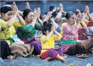  ??  ?? Asking for help . . . Balinese citizens pray for safety on the beach near Mt Agung, a volcano on the highest alert level, outside the current danger zone in Amed, on the resort island of Bali, Indonesia.