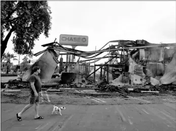  ?? AP Photo/Gregory Bull ?? A man passes a bank burned during a protest over the death of George Floyd, on Sunday in La Mesa.