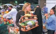  ?? PAUL HACKETT / REUTERS ?? Volunteers deliver food near the gutted Grenfell Tower, where the death toll had risen to 17 on Thursday.