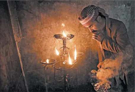  ?? SAFIN HAMED/GETTY-AFP ?? An Iraqi
Yazidi lights candles and paraffin torches near a temple far outside Baghdad to welcome the Yazidi New Year, which began Wednesday.