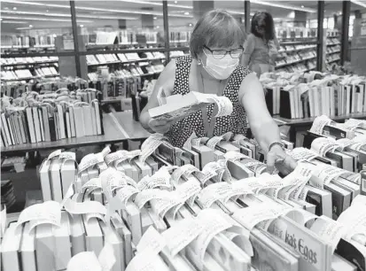  ?? BARBARA HADDOCK TAYLOR/BALTIMORE SUN FILE ?? Mary Doyle, a circulatio­n assistant at the Cockeysvil­le branch of the Baltimore County Public Library, looks for books for a library patron in the library’s hold room. Baltimore County library employees are seeking the ability to organize a union and negotiate for health care benefits for parttime staff.